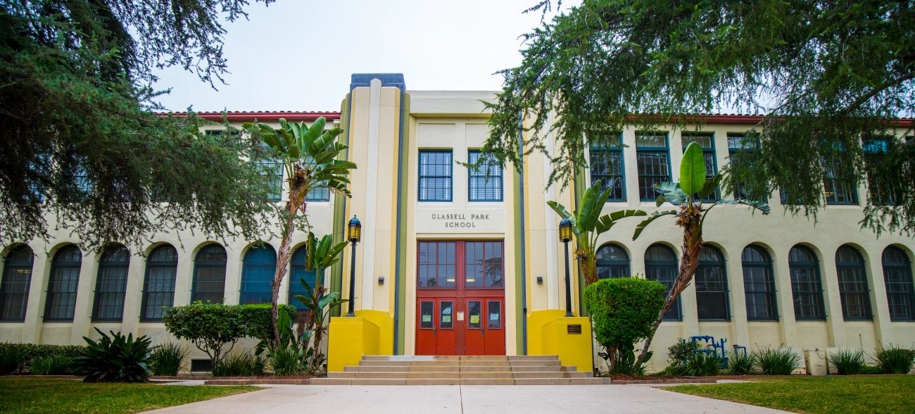 The front elevation of Glassell Park Elementary School, a two storey Art Deco building with an arched arcade and a yellow and red entrance bay.