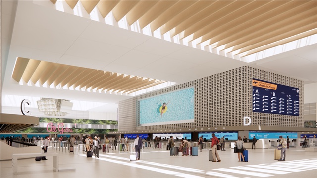The check in hall seen from the concourse, ribbed ceiling above, a wide digital display between the check in zones and the departure boards to the right.