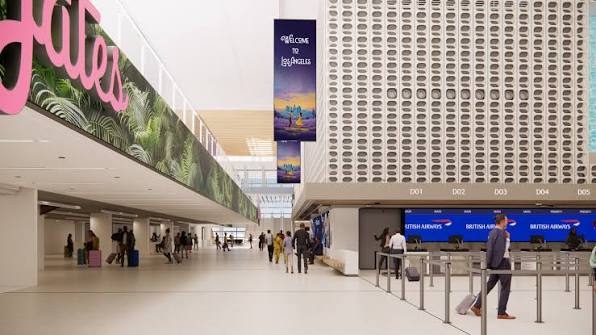 The concourse below the ticketing level, planting along a raised edge, a tall digital column reading Welcome to Los Angeles, and airline counters to the right.